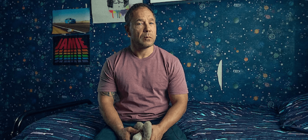 "Stephen Graham as Eddie Miller sitting on a bed, looking emotional in Netflix’s Adolescence series."